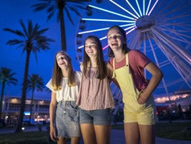 girls in front the Ferris Wheel at The Wharf at night